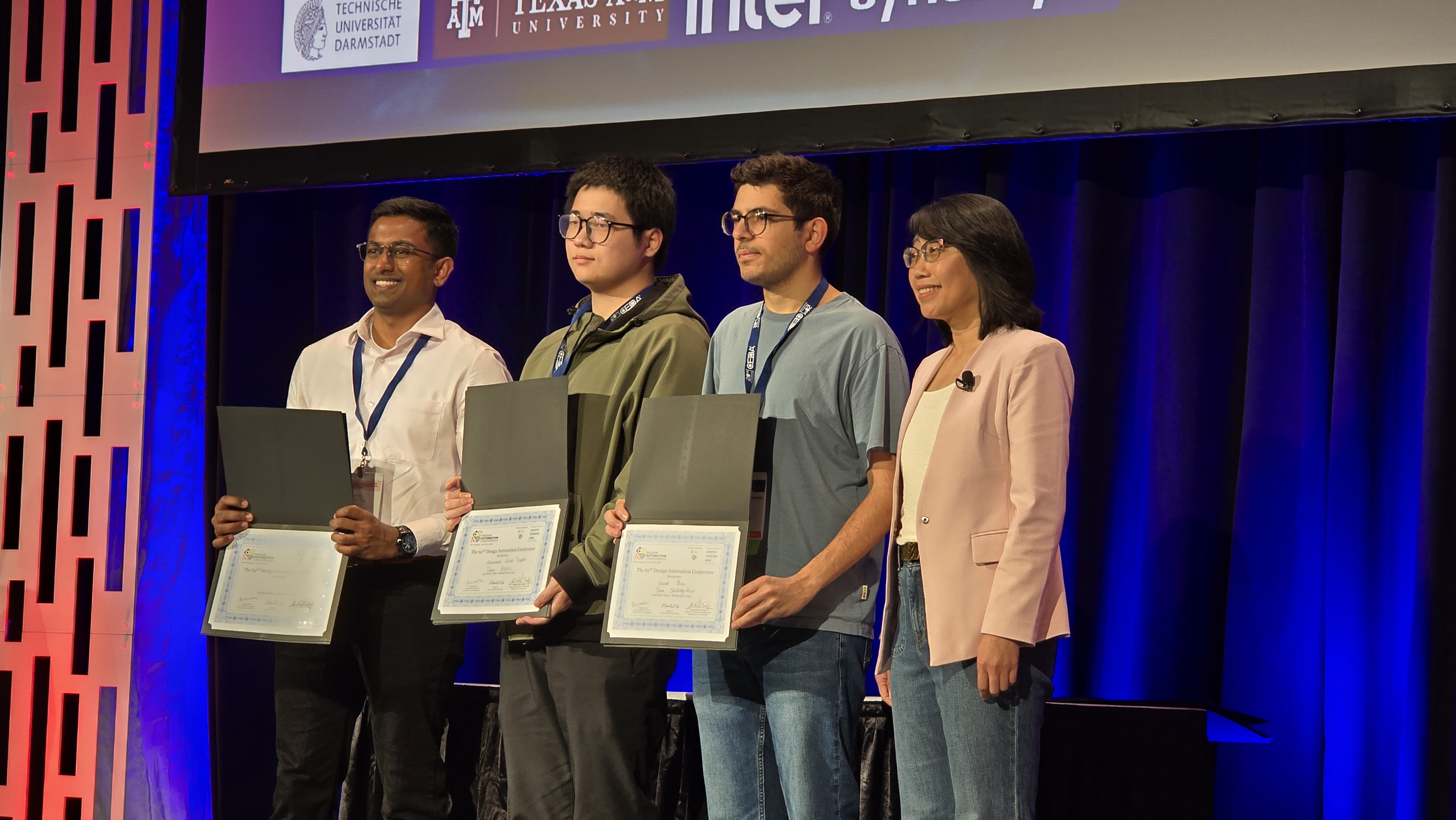 People pose on stage holding award certificates