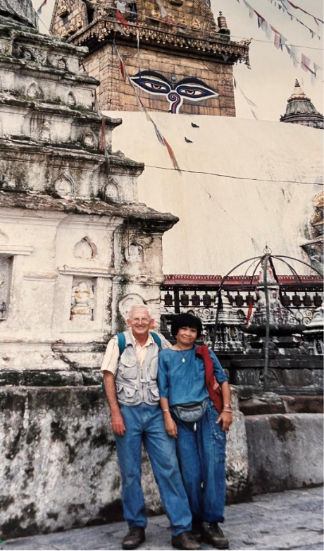 Two people standing together in front of a temple structure with decorative carvings.
