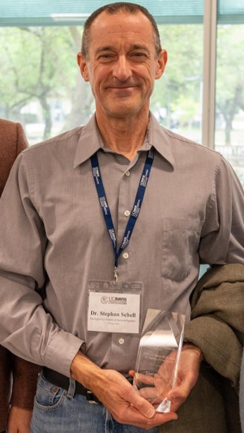 image of Stephen Schell holding his alumni award