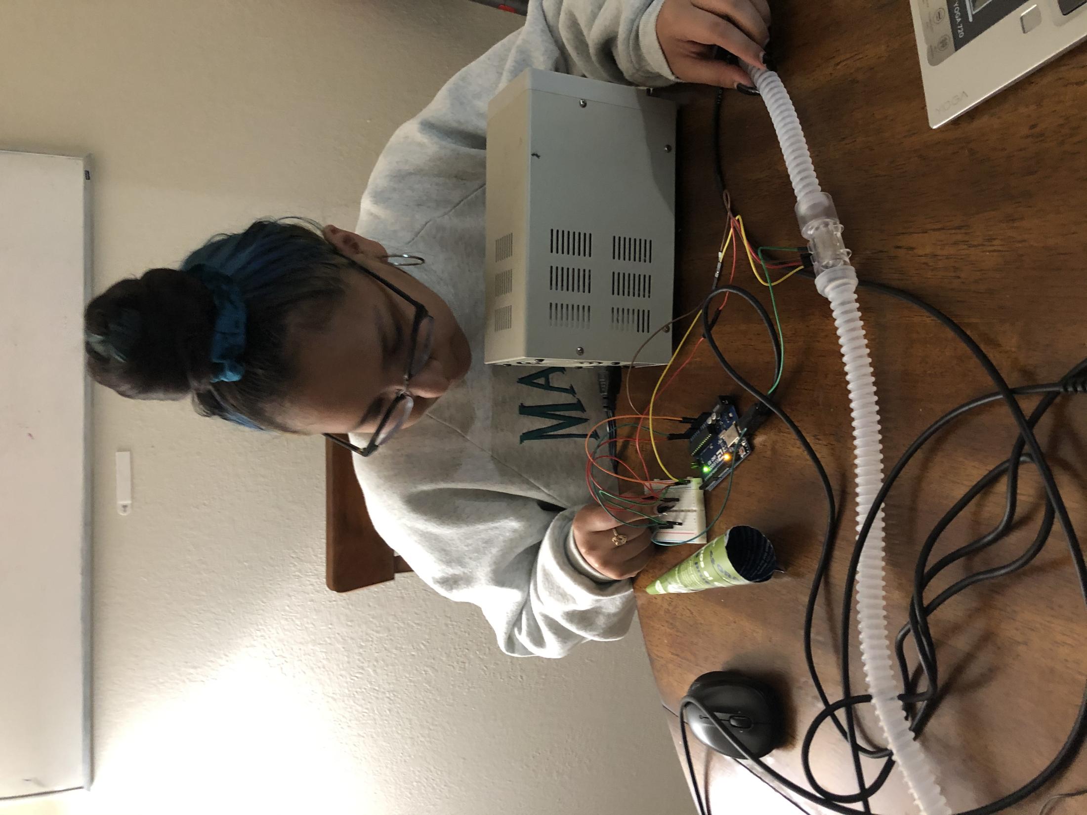 Young woman sitting at a table testing a flow sensor