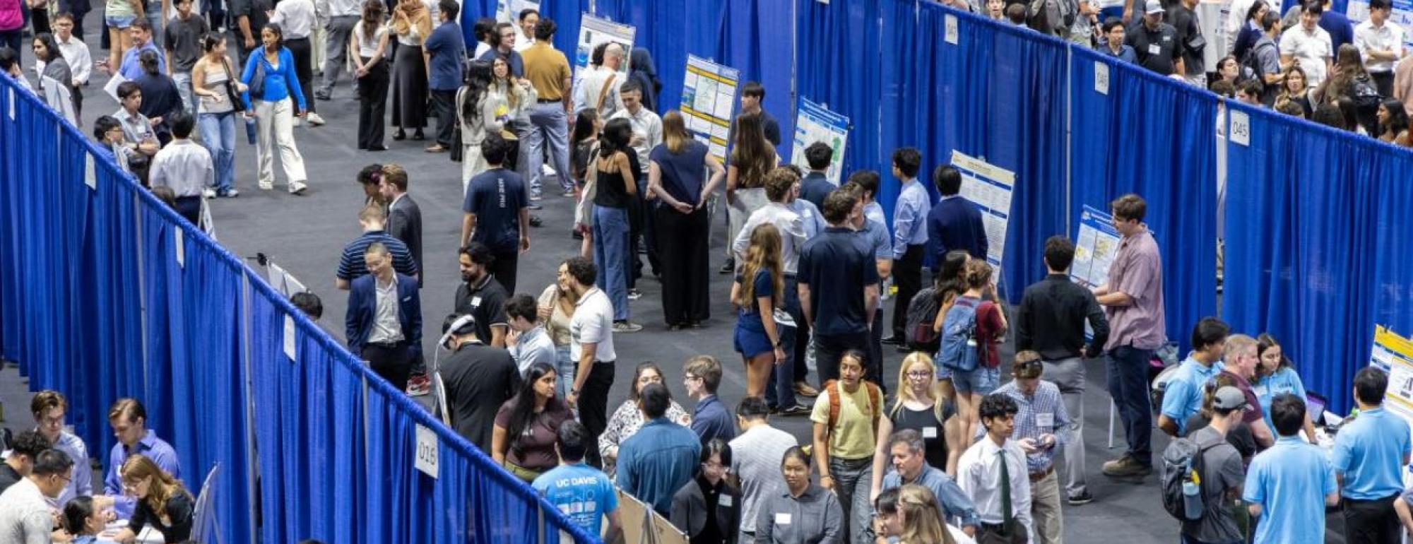 Student teams presenting their projects in a large room