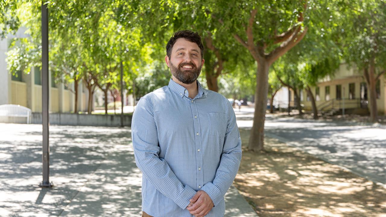 Noah Glick stands outdoors with arms together