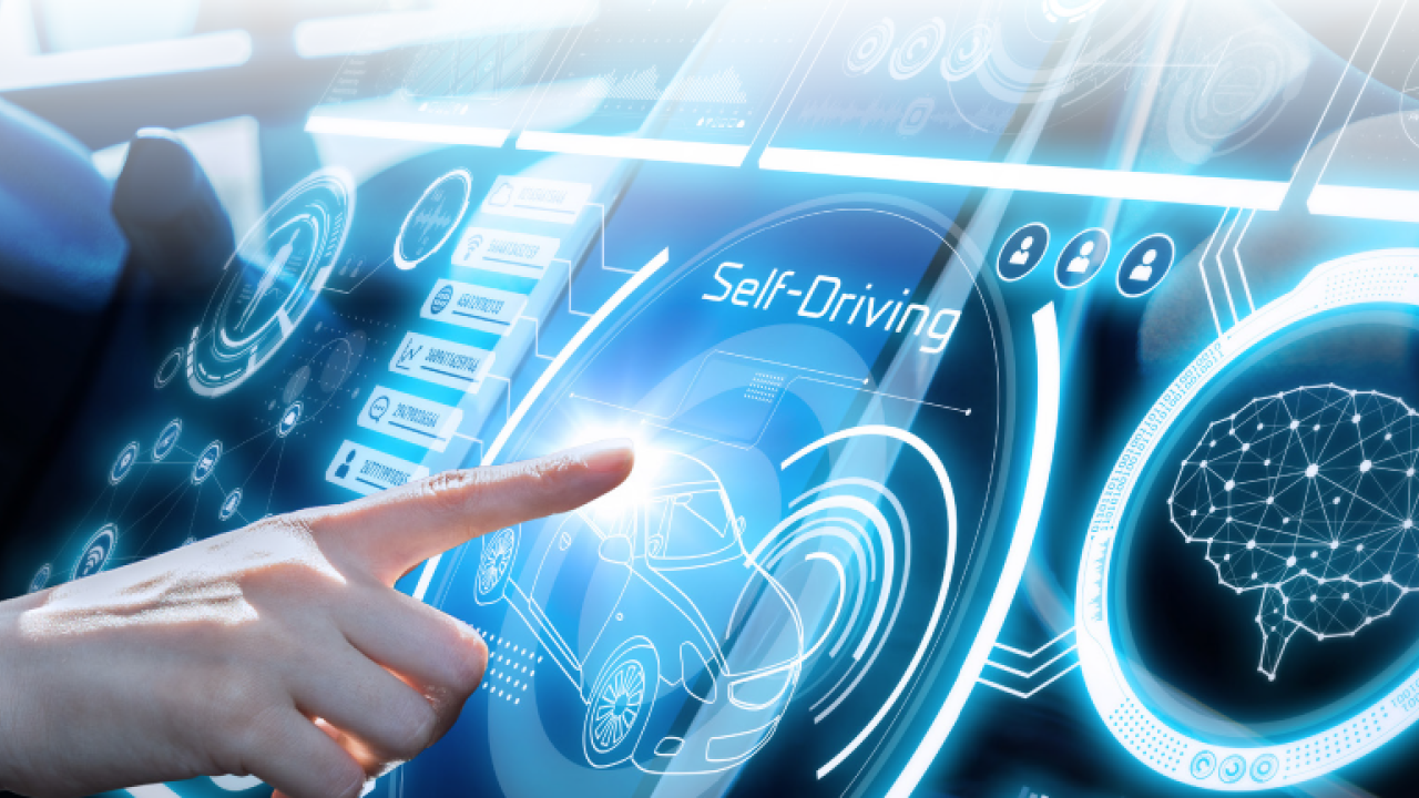 Futuristic looking car interior with blue lighting and a hand outstretched to push a self driving button