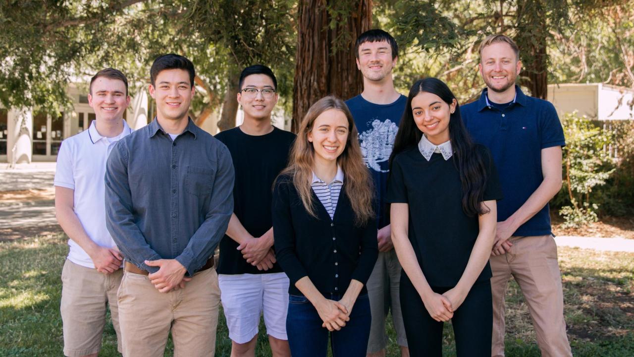 group of students standing with hands clasped
