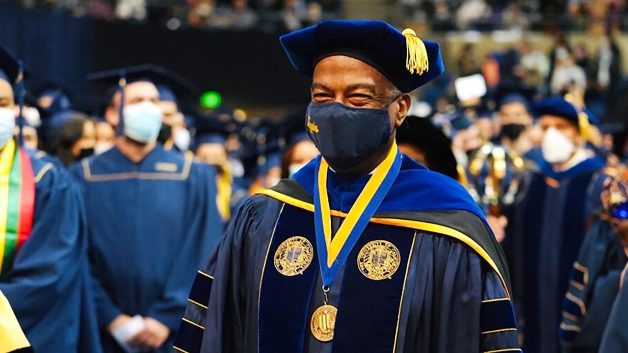 Middle aged Black man in a blue graduation gown at a ceremony