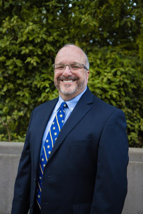 A man in a suit and tie smiles
