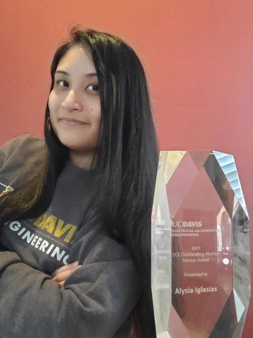 Young Latina woman sitting next to an award plaque