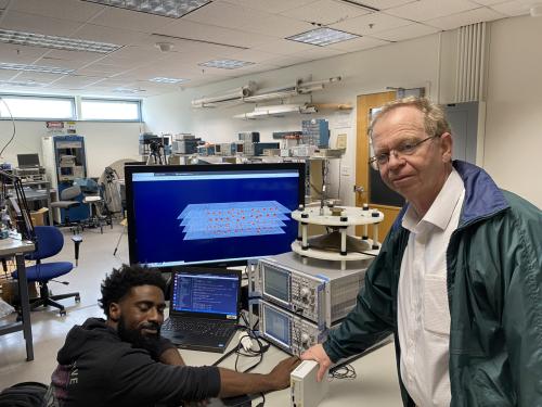 Two men work on a computer within a lab