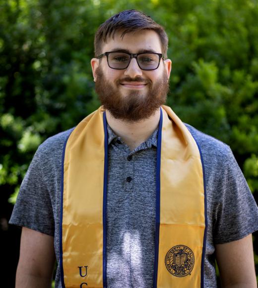 A man stands with a UC Davis-branded stole