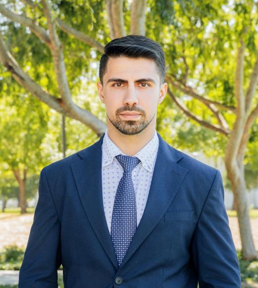 image of Michael in a blue suit and tie, blurred outdoor background
