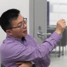 Professor Zhang wearing a collared shirt, talking with his hand outstreched