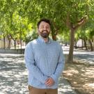 Noah Glick stands outdoors with arms together