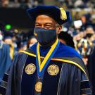 Middle aged Black man in a blue graduation gown at a ceremony